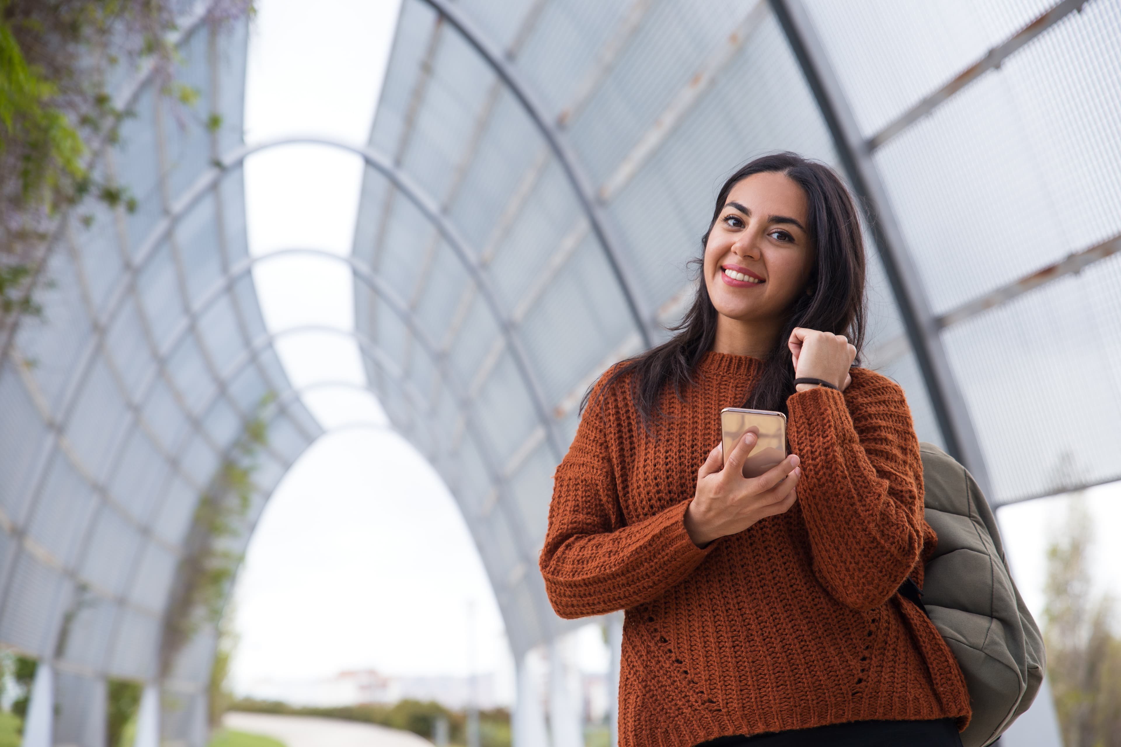 A cheerful aspirant walking with her phone